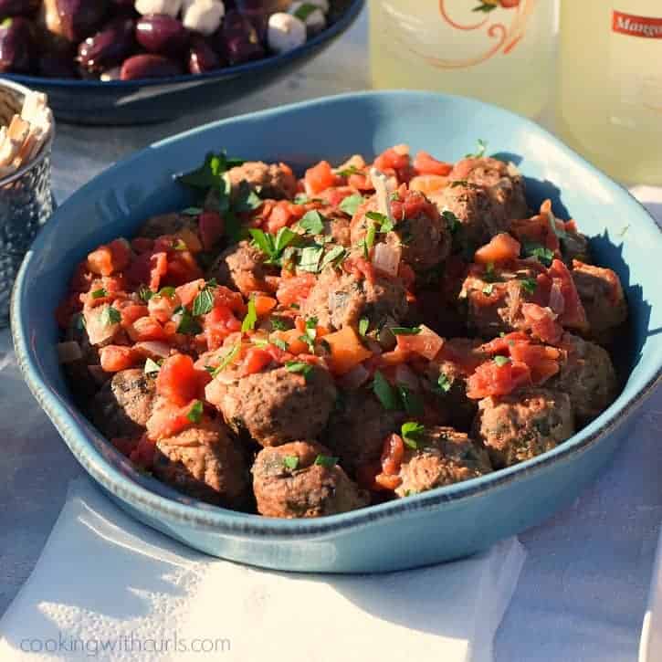 A large bowl filled with meatballs in tomato sauce sitting outside on a white table cloth.