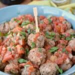 a blue bowl filled with meatballs and sitting on a yellow striped napkin