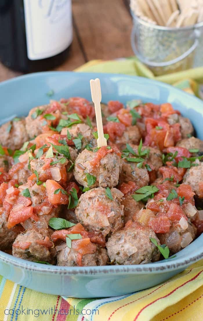 a blue bowl filled with meatballs and sitting on a yellow striped napkin.