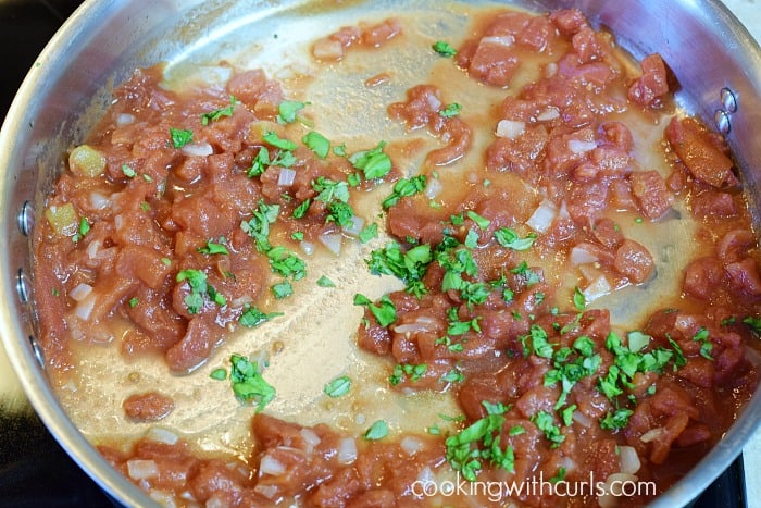 Diced tomatoes mixed with the diced onions and parsley in the skillet.