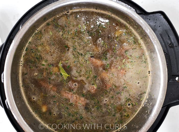 Beef stock, beer, carrots, potatoes, beef, barley, thyme and bay leaves added to the pressure cooker. 