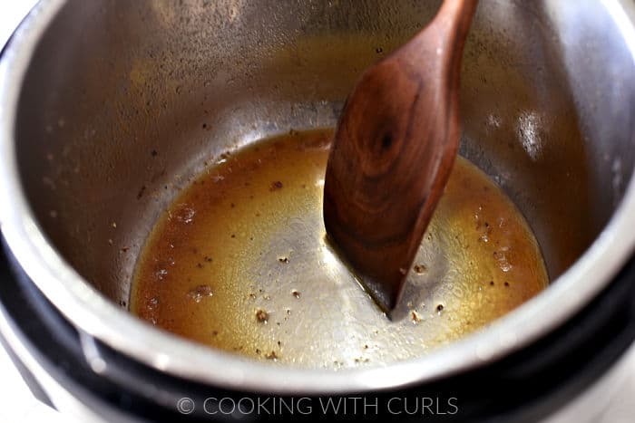 Beef stock used to deglaze instant pot using a wooden turner. 