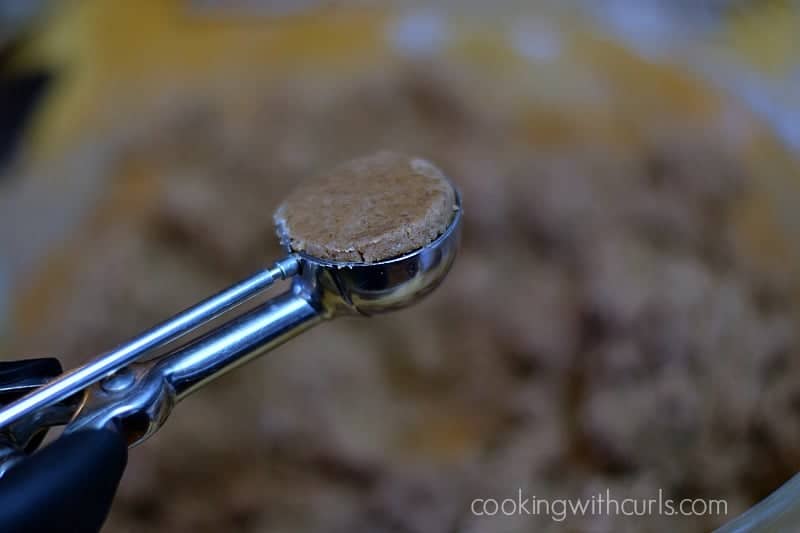 A metal cookie scoop full of chocolate cookie dough.