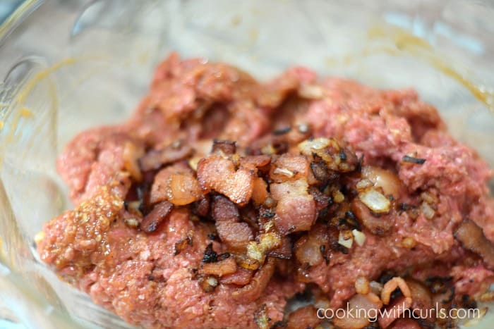 Ground beef, cooked bacon pieces and onions in a large glass bowl.