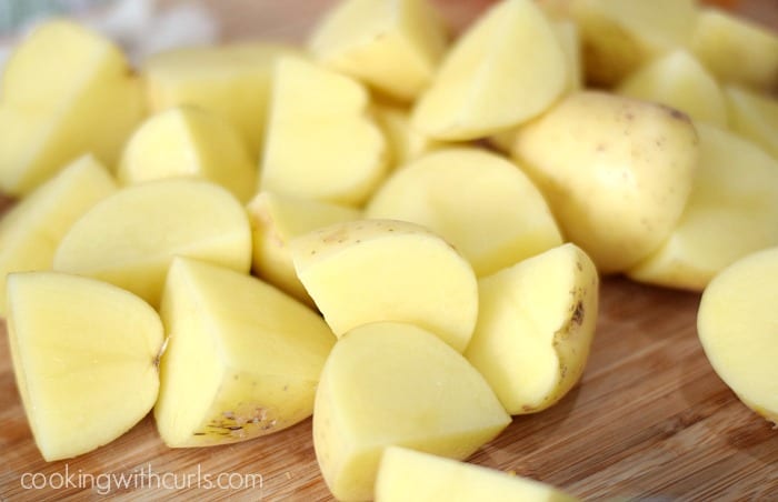 Chopped potatoes chunks on a wood cutting board.