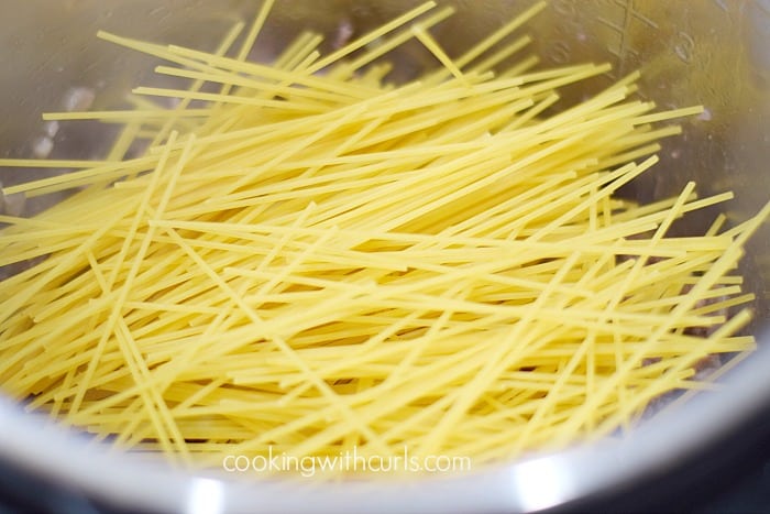 Boxed spaghetti noodles added on top of cooked beef in an Instant Pot.