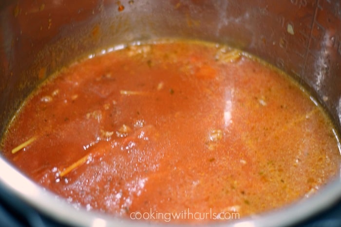 Spaghetti sauce, noodles, and cooked ground beef in an Instant Pot.