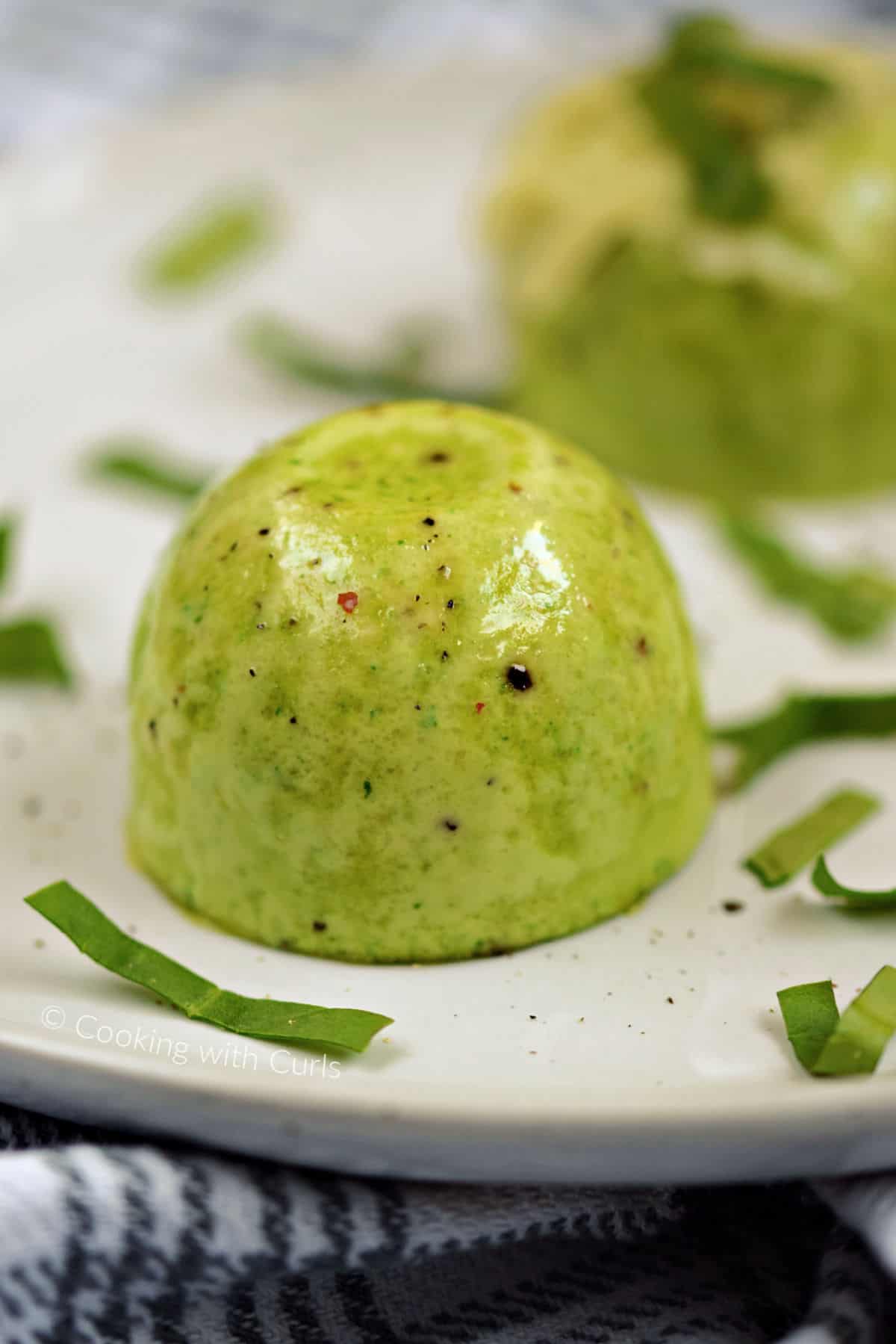 Two green spinach and cheese egg bites on a plate.