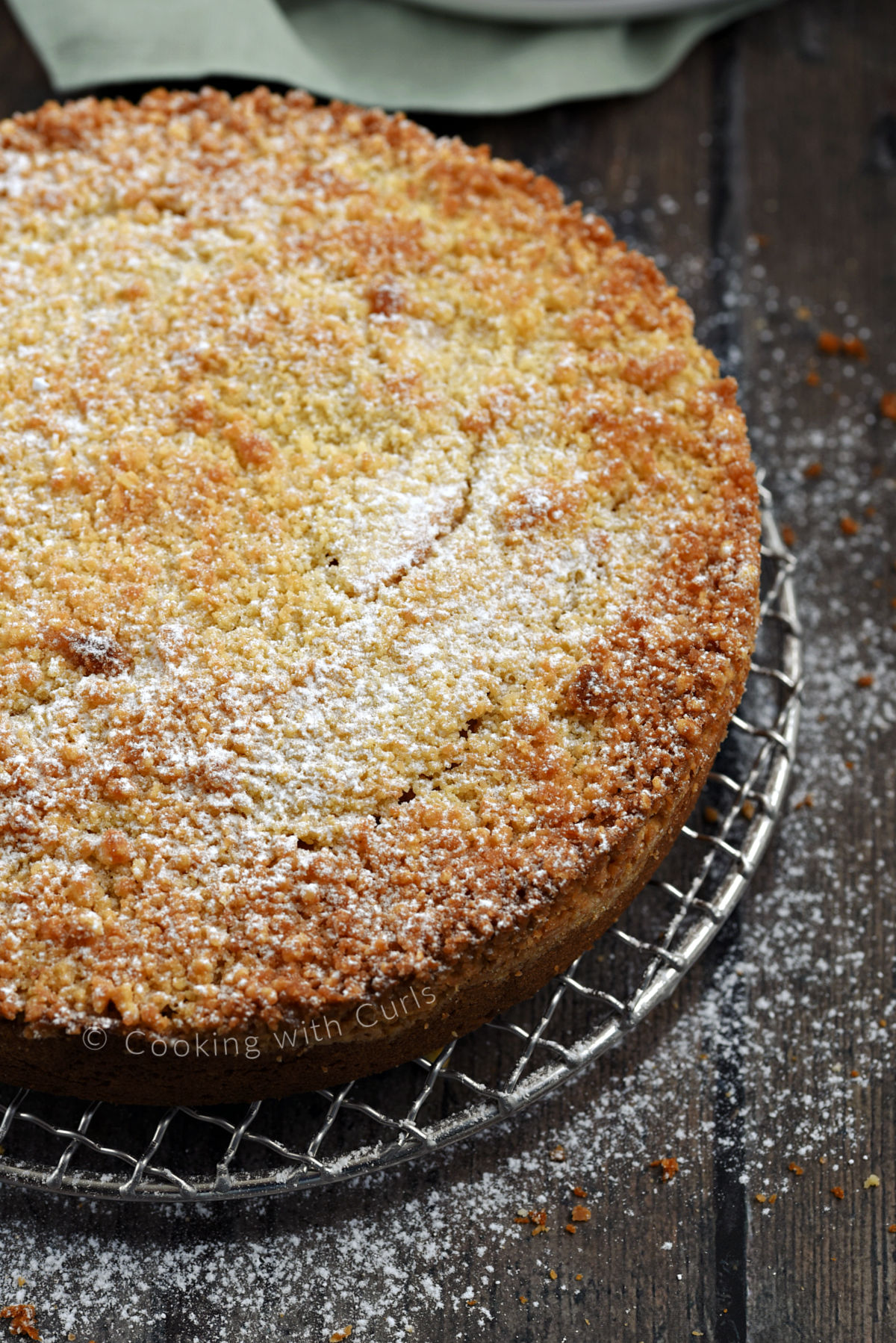 Irish Apple Cake dusted with powdered sugar on a round wire rack. 