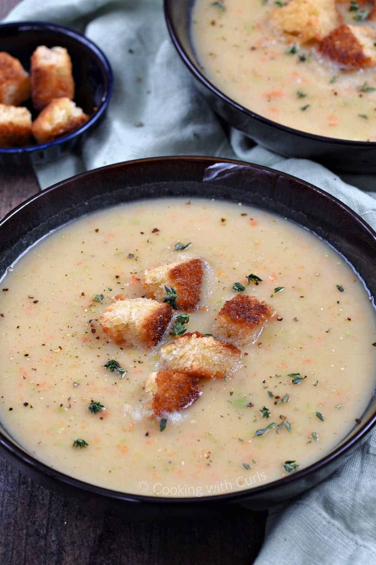 A bowl of Irish vegetable soup topped with sourdough croutons and fresh thyme.