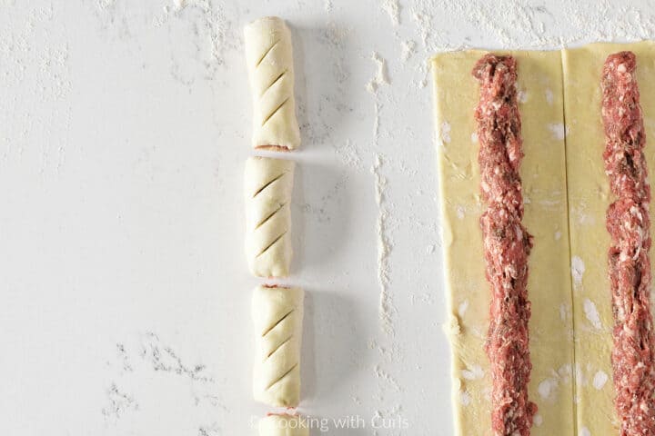 One row of cut sausage rolls and two rows of sausage on puff pastry dough.