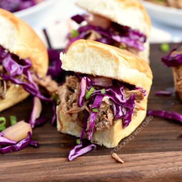 Hawaiian Pulled Pork sandwiches topped with pineapple slaw sitting on a wood board