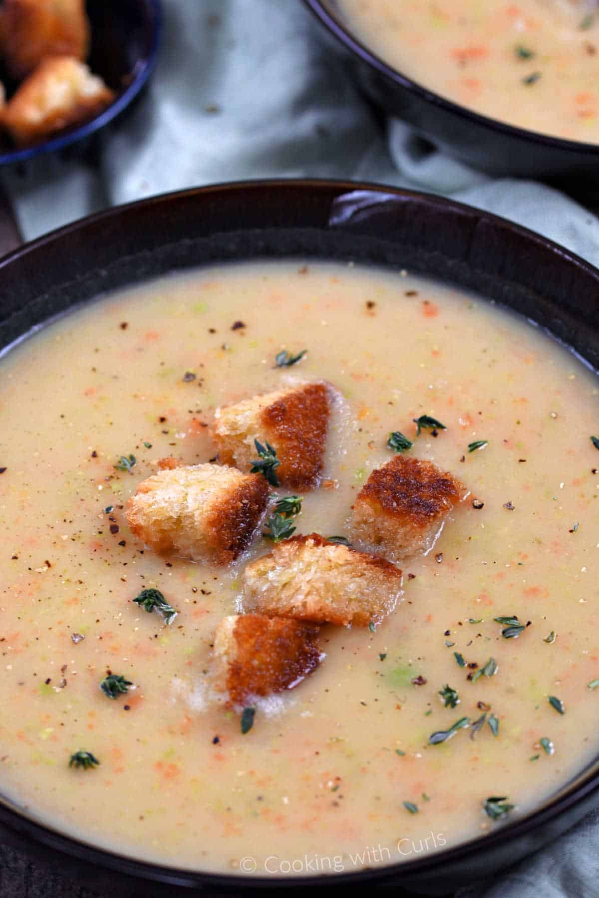 Two bowls of Irish vegetable soup topped with croutons and fresh thyme.