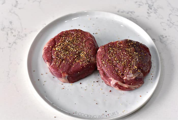 two seasoned beef tenderloin filets on a white plate. 