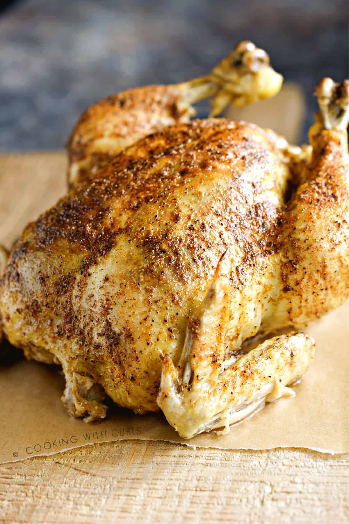 A whole pressure cooked chicken  sitting on a wooden cutting board.